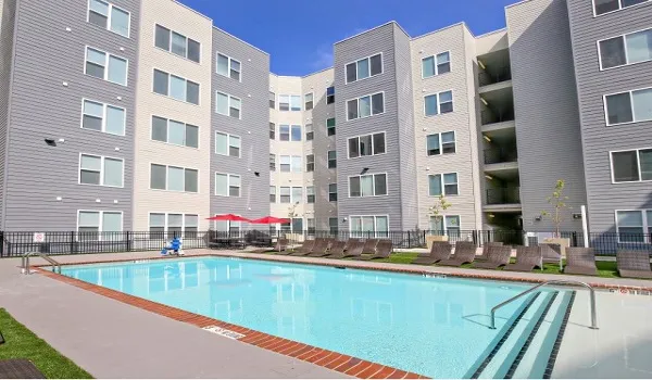Outdoor swimming pool with sun loungers in front of a residential block