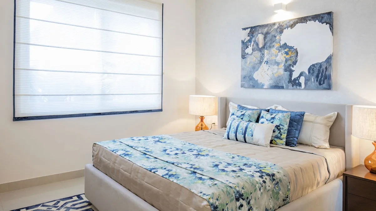 Second bedroom in blue and beige with a shuttered window and patterned bed runner