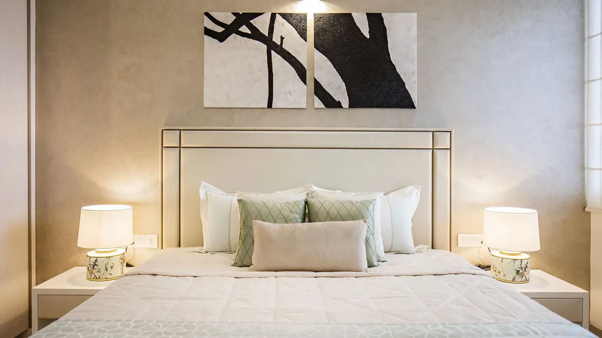 Bedroom with an upholstered headboard, matching bedside lamps and a two panel artwork