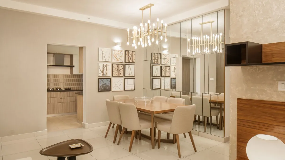 Dining area with six upholstered chairs beneath a brass chandelier and a mirrored wall