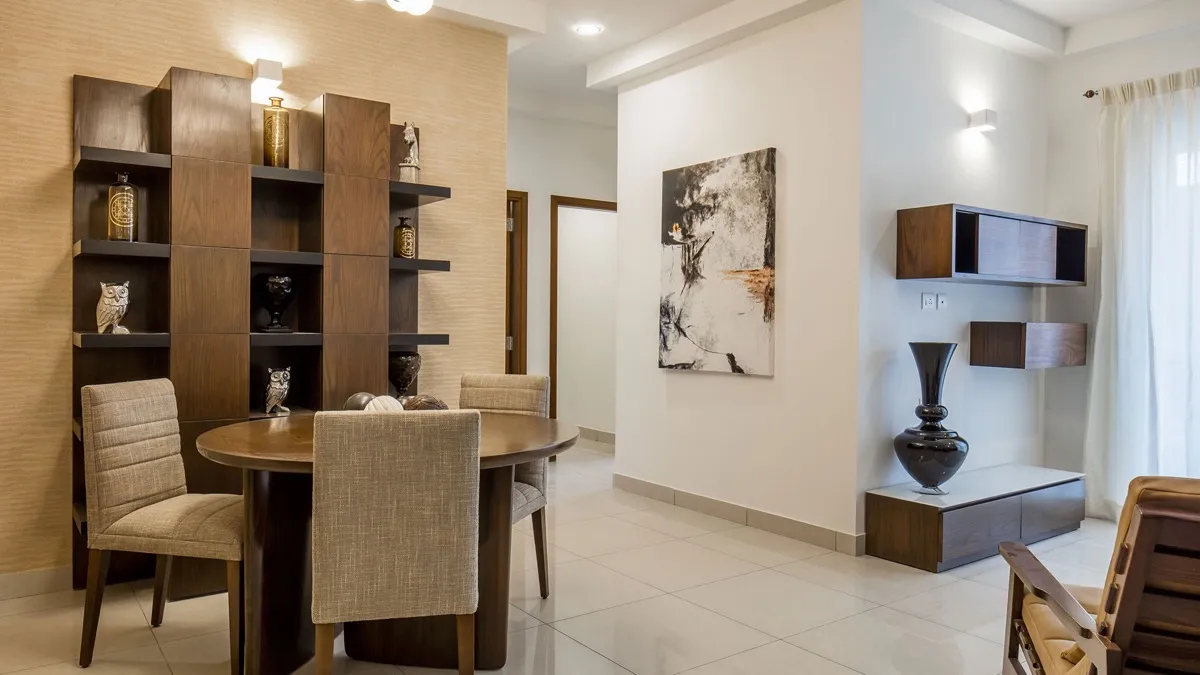 Study corner with an open timber shelving unit, round table and wall mounted cabinets