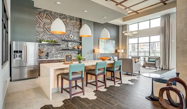 Clubhouse lounge with an island counter, bar stools and armchairs by a full height window