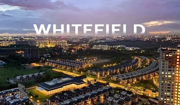 Aerial view of Whitefield at dusk with lit streets, low rise housing and tower blocks